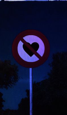 a no heart sign lit up at night with trees in the backgrouund