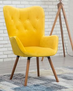 a yellow chair sitting on top of a wooden floor next to a white brick wall