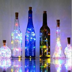 several bottles with lights in them sitting on a table