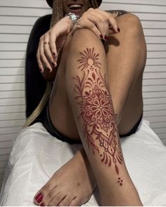 a woman sitting on top of a bed with tattoos on her arms and legs,