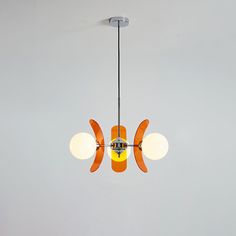 an orange and yellow light fixture hanging from the ceiling in front of a white wall