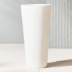 a tall white vase sitting on top of a table