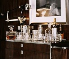 an assortment of liquor bottles and glasses sitting on a bar with a framed photograph in the background