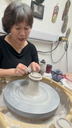 a woman is making a vase out of clay