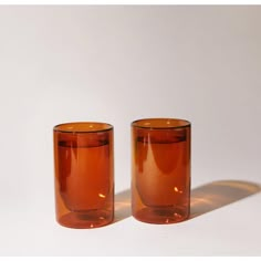 two orange glass cups sitting on top of a white table