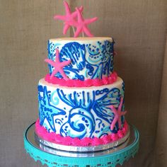 a three tiered cake decorated with pink and blue icing, stars and sea creatures