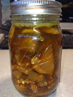 a jar filled with pickles sitting on top of a counter next to a computer