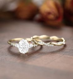 two wedding rings with one diamond on top and the other in the middle, sitting on a table