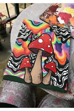 someone is holding up a colorful mushroom painting