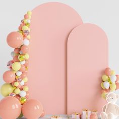 a pink wall with balloons and decorations on it