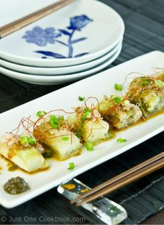 some food is on a white plate with chopsticks next to it and two plates