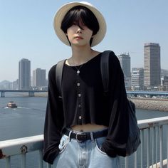 a mannequin wearing a hat standing on a bridge overlooking the water with boats in the background