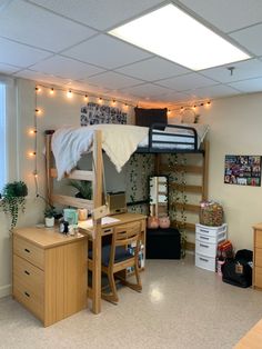 a dorm room with bunk beds, desks and lights hanging from the ceiling above