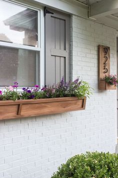 a window box filled with purple flowers next to a white brick building