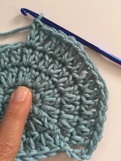 a crochet pattern being worked on by someone using a blue knitting needle and yarn