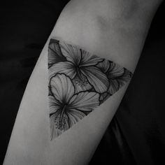 a black and white photo of some flowers on the side of a woman's arm