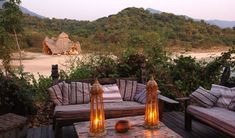 an outdoor seating area with candles lit on the table and two couches in front of it