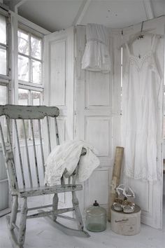 an old rocking chair in the corner of a room with white walls and curtains on it