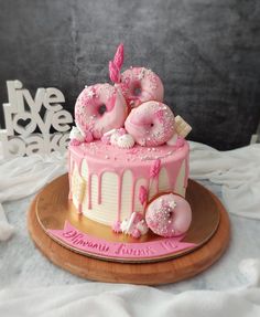 a pink and white cake with donuts on top