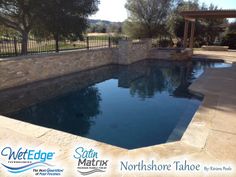 a large swimming pool surrounded by stone walls and fenced in area with water feature