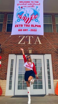 a woman is posing in front of a building with a sign that says zera tau alpha