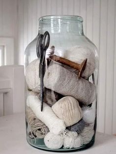 a glass jar filled with yarn and scissors