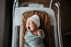 a baby is yawning while laying in a stroller