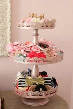 three tiered cake stand with flowers and ribbons on it