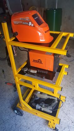 an orange machine sitting on top of a yellow cart