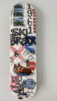 a skateboard with various stickers on it sitting up against a white wall,