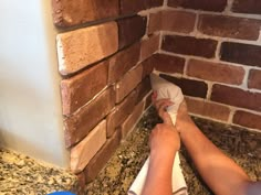 a person laying on the ground in front of a brick wall with their feet up