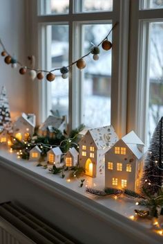 a window sill decorated with christmas lights and small houses on the windowsills