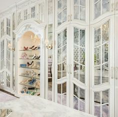 a white closet filled with lots of shoes and other items in it's glass doors