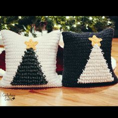 two crocheted christmas pillows sitting on top of a wooden floor next to a tree