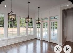 an empty living room with wood flooring and chandelier hanging from the ceiling