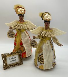 "Introducing new African Queen Angel Figurines and Tree Toppers.  If your world is filled with bright and bold colors, these Angels will add bright Afrocentric Vibes to your home decor.  Select your style of Orange or White at Checkout. About the African Queen Angel, dressed in Orange, Gold and Metallic Zig Zag Print. Made to Order. *  Handcrafted, she is a 15 1/2 Inch Angel, featuring a vinyl head, hands with poseable arms, attached to a sturdy open bottom cone. *   Her dress is made in paisley prints and metallic gold fabric in orange or white. The long-sleeve caplet, adorned with gold trim, accented with gold ribbon tied around her waist and bow-tied in the front. Her accented zig zag pleated lapel cascades down the side. *  Crowned with a matching headpiece, she wears a beaded necklace Angel Tree Topper, Zig Zag Print, Angel Tree, Black Dolls, White Wings, African Queen, African Wax Print, Angel Figurines, Gold Ribbon