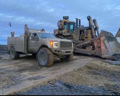 a large dump truck parked on top of a dirt field next to a bulldozer