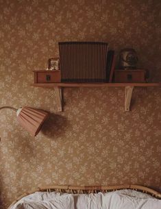 a bedroom with a bed, lamp and radio on top of the shelf above it