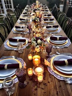 a long table set with place settings and candles for an outdoor dinner party or gathering