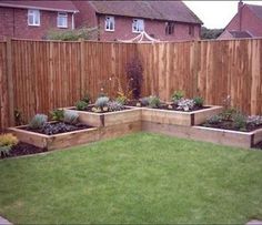 a backyard garden with grass and wooden fenced in areas that have plants growing on them