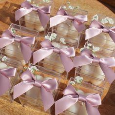 small clear boxes filled with cupcakes covered in pink ribbon and white flowers on a wooden table