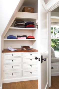 an open closet with white drawers and shelves