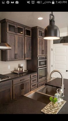 a kitchen with dark wood cabinets and black counter tops, an island in the middle