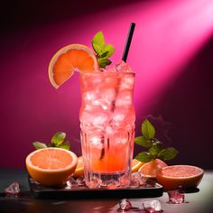 a drink with ice, orange slices and mint on a tray in front of a pink background