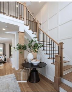 there is a vase with some plants on the table in front of the stair case