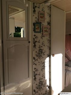 an open door leading to a bedroom with floral wallpaper