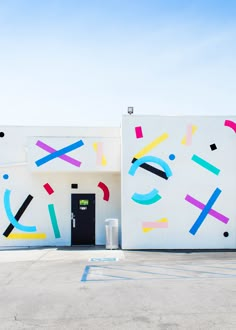 a white building with multicolored lines painted on it's side and a black door