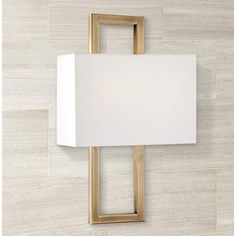 a wall mounted lamp with a white shade on it's face and gold frame