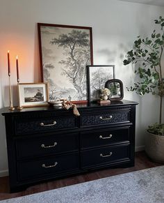 a black dresser with candles and pictures on it