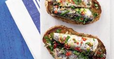 two pieces of bread with different toppings on them sitting on a blue and white napkin